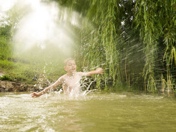 Boy splashing water while playing in lake