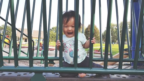 Portrait of cute baby girl playing on jungle gym at playground