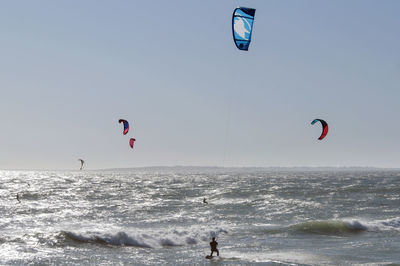 Rear view of man kitesurfing on sea against sky