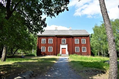 House by trees and building against sky