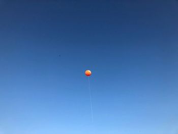 Low angle view of balloons against clear blue sky