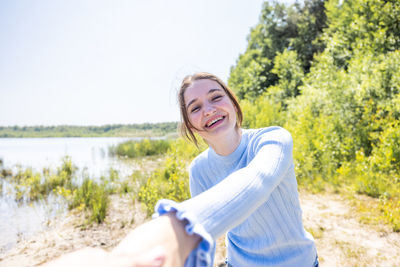 Portrait of young woman standing against lake