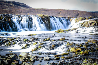 Scenic view of waterfall against sky during winter