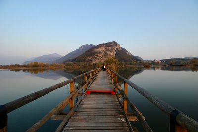 Pier over lake against clear sky