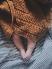 Low section of newborn baby boy wrapped in blanket on bed