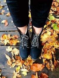 Low section of person standing on autumn leaves