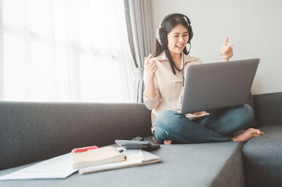 Young woman using mobile phone while sitting on sofa