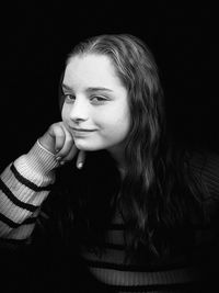 Close-up portrait of a beautiful young woman over black background