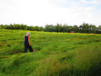 Rear view of woman walking on grassy land
