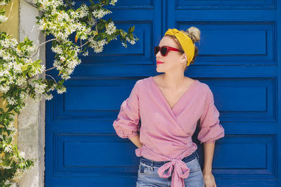 Woman in sunglasses looking away while standing against door