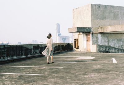 Rear view of woman standing against sky in city