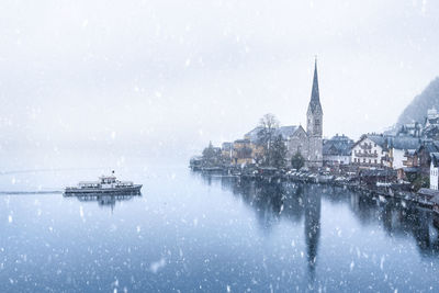 Church by sea against sky during snowfall