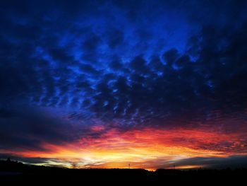 Silhouette landscape against dramatic sky during sunset