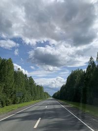 Empty road along trees and against sky