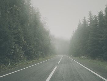 Road amidst trees against sky during rainy season