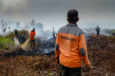 Rear view of men working on field