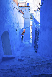 Narrow alley of blue town with staircase leading to residential structures on both side