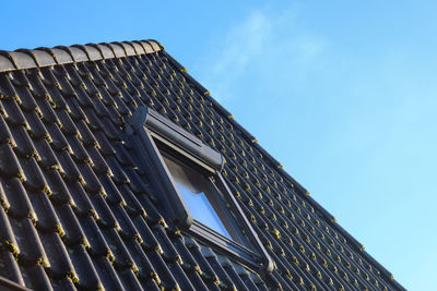 Open roof window in velux style with black roof tiles