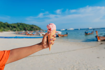 Cropped hand of woman holding seashell at beach