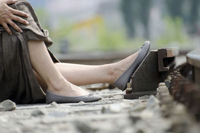 Low section of woman sitting on railway track