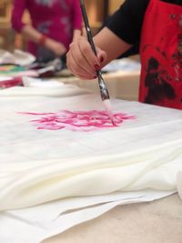 Midsection of painter painting flower on textile