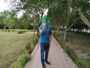 Full length of man using mobile phone while standing on plants