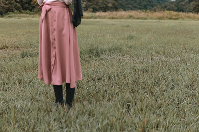 Low section of woman standing on field