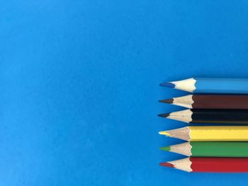 High angle view of colored pencils against blue background