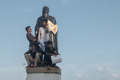 Low angle view of friends standing against sky