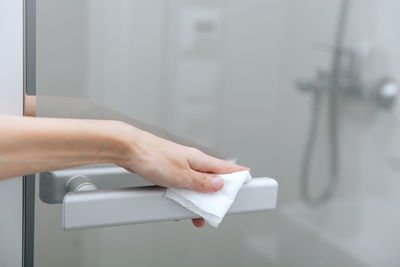 Cleaning glass door handles with an antiseptic wet wipe. woman hand using 