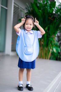 Smiling girl gesturing while standing on sidewalk