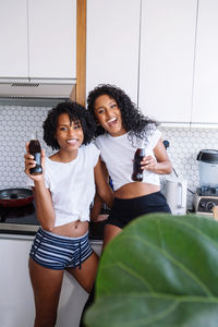 Two black women drinking coca cola in their kitchen