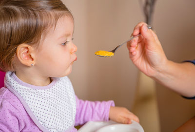 Cropped image of mother feeding baby girl