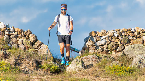 Full length of man standing on rock against sky