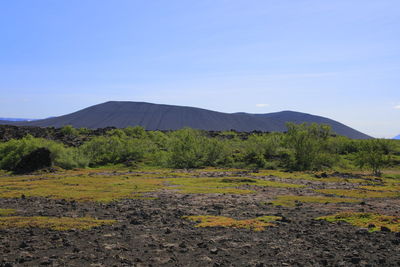 Scenic view of land and mountains against clear blue sky