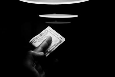 Close-up of hand holding electric lamp against black background