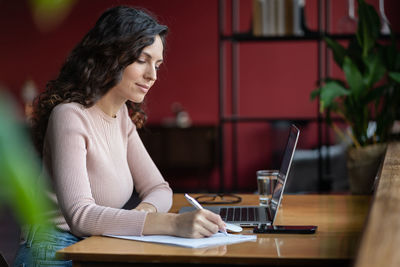 Focused girl study on laptop make notes. concentrated small business owner with pc write in notebook