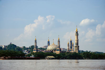 Buildings by sea against sky