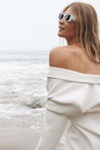 Portrait of young woman wearing sunglasses while standing at beach