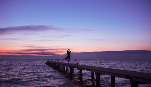 Silhouette man standing on pier over sea against sky during sunset