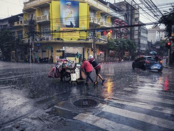 People on wet street in city during rainy season