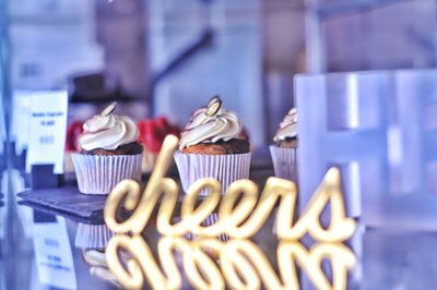 Close-up of cupcakes with cheers sign reflected in foreground 