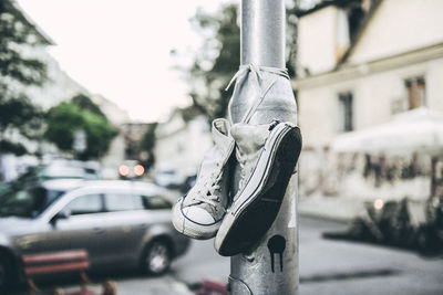 Close-up of canvas shoes tied on light pole at street
