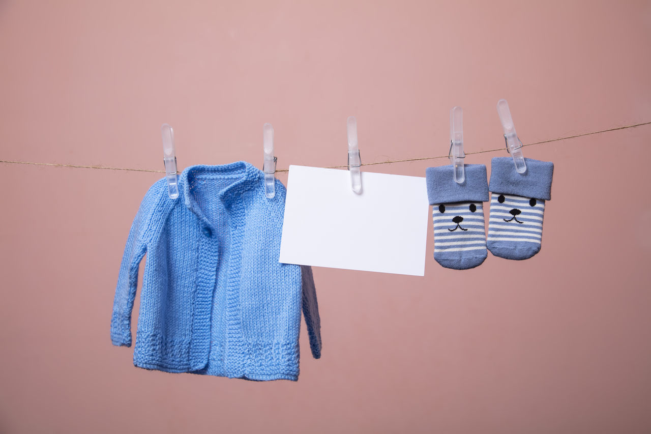 CLOSE-UP OF CLOTHES DRYING AGAINST BLUE WALL