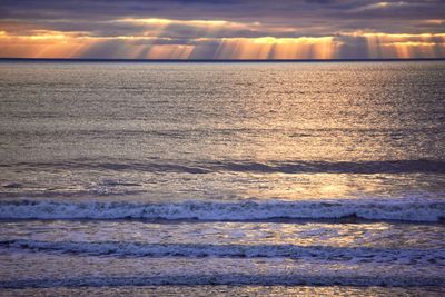 Scenic view of sea against dramatic sky during sunset