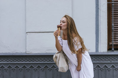 Young woman standing against wall