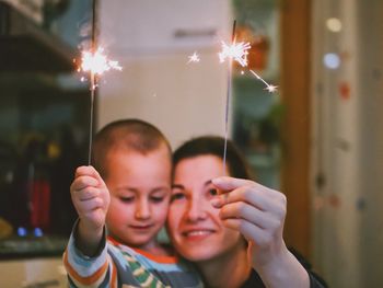 Close-up of mother and son playing with burning sparklers