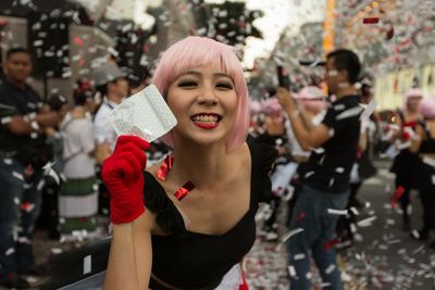 Portrait of smiling young woman with pink hair standing on city street