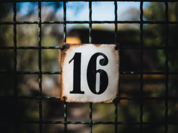 Close-up of information sign on metal fence