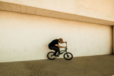 Man riding bicycle against wall